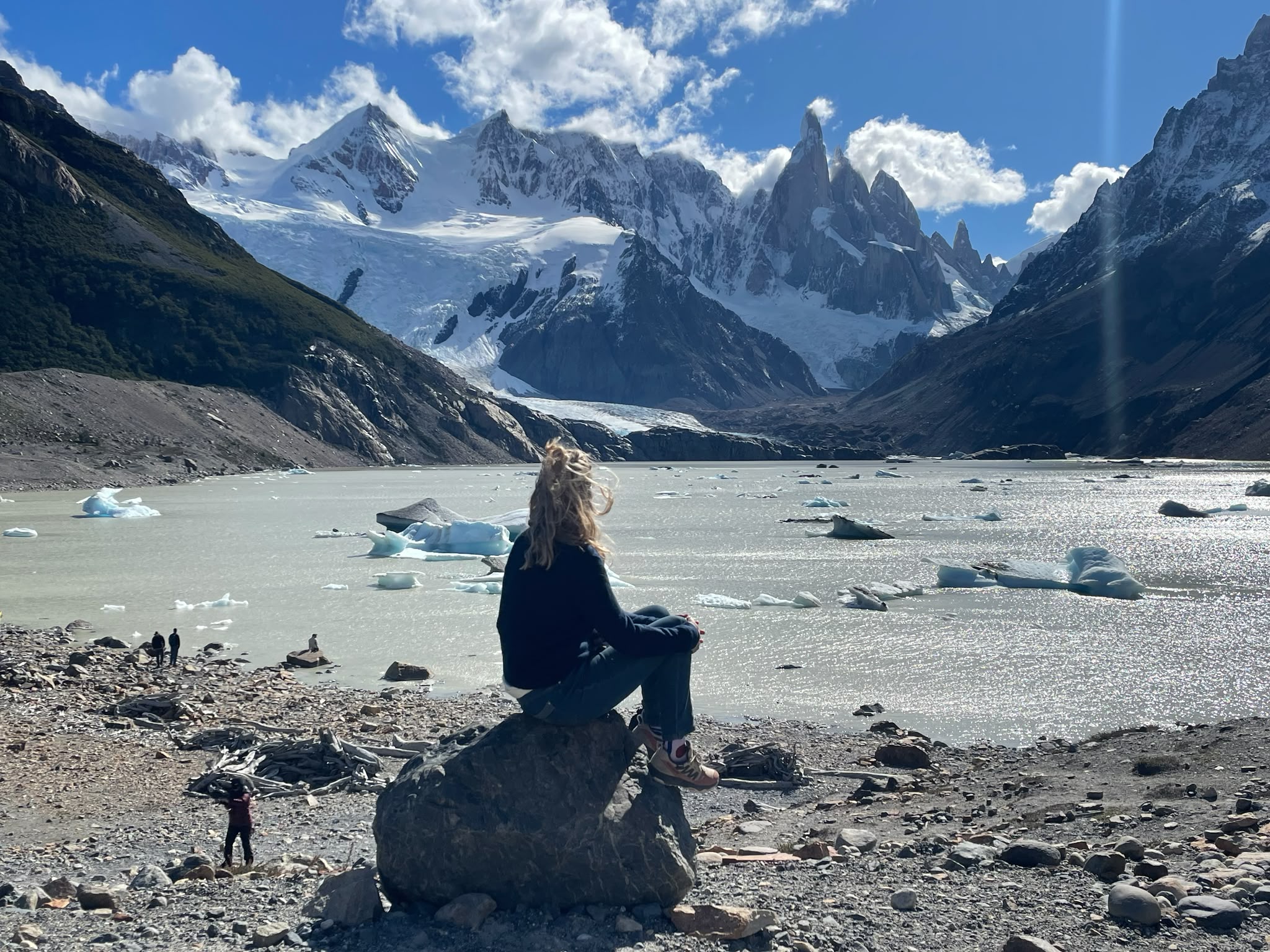 Une femme assise face à un lac glaciaire au lever du soleil, dans la contemplation